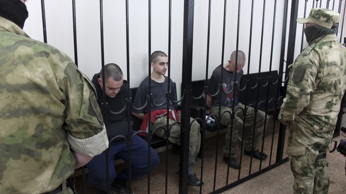 Two British citizens Aiden Aslin, left, and Shaun Pinner, right, and Moroccan Saaudun Brahim, center, sit behind bars in a courtroom in Donetsk, in the territory which is under the Government of the Donetsk People's Republic control, eastern Ukraine, Thursday, June 9, 2022. Photo / AP