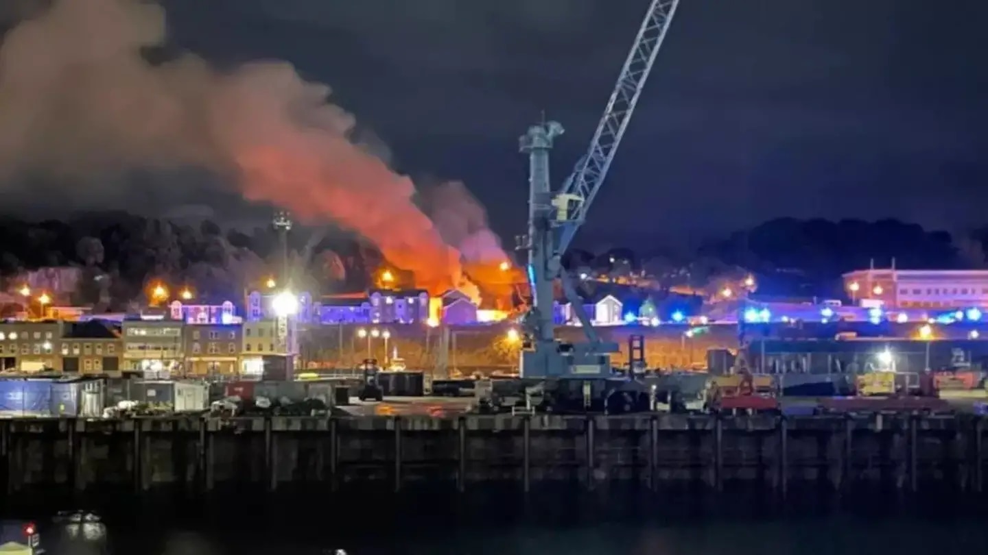 Smoke and flames can be seen after an explosion in an apartment building in Jersey that has killed at least three people and left about a dozen missing. Photo / Supplied