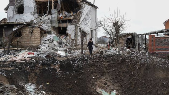 A woman stands on top of a crater next to a destroyed house after a Russian rocket attack in Hlevakha, Kyiv region, Ukraine, on Thursday, a day after the US and Germany announced sending powerful high-tech tanks to Ukraine. Photo / AP