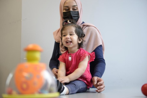 In this photo provided by the Children's Hospital of Eastern Ontario, Ayla Bashir sits with her mother, Sobia Qureshi, during a physical therapy assessment for Ayla at CHEO in Ottawa on Aug. 23, 2022. The toddler is the first child treated as fetus for Pompe disease, an inherited and fatal disorder in which the body fails to make some or all of a crucial protein. (André Coutu/CHEO via AP)