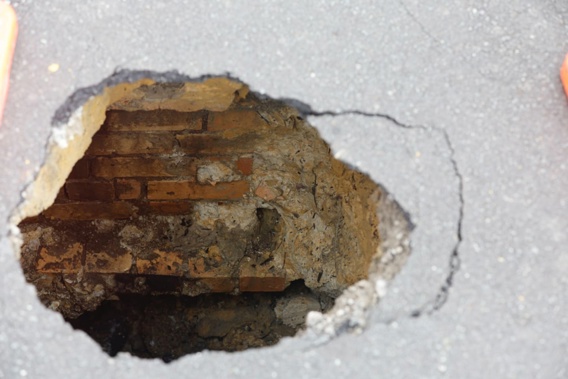 A sinkhole has a brick-lined crater that is around 2sqm beneath the ruptured surface of the St Marys Bay street. Photo / Michael Craig