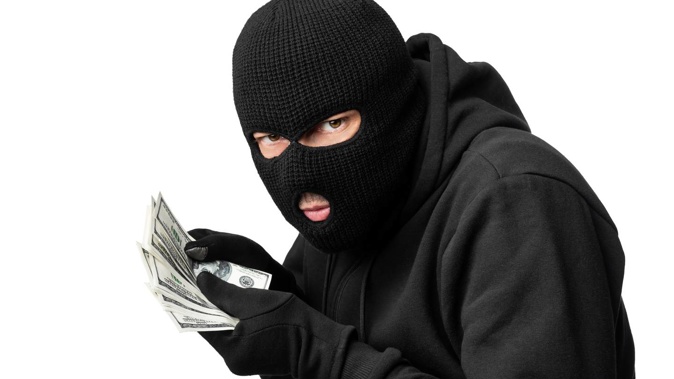 A robber disguised in a balaclava apologised to a worker in a hair salon who confronted him as he was stealing cash from the till