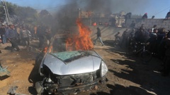 Palestinians watch a car burn after it was hit by an Israeli strike in Rafah, Gaza Strip. Photo / AP