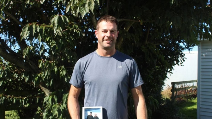 Simon Adams holding an image of himself and his son Jordy, who drowned in 2021. Photo / Alyssa Smith