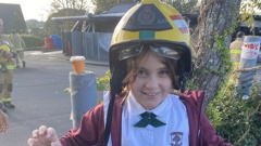 Schoolgirl Harper Davis wearing a firefighter's helmet outside the scene of the blaze.