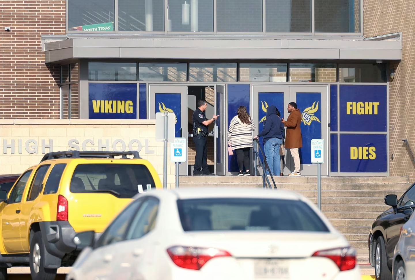An Arlington police officer speaks to individuals outside of Lamar High School in Arlington during a lockdown after shooting. Photo / AP