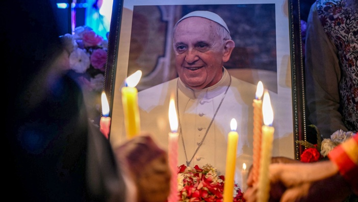 People light candles as they pay respects in front of a portrait of Pope Francis during a condolence meeting in New Delhi, following the news of his death. Photo / AFP