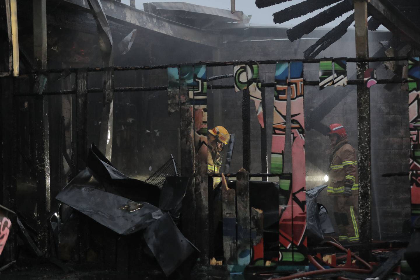 Firefighters stand in what is left of a building after a fire in Royal Oak. Photo / Michael Craig