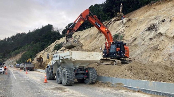 A digger moves some of the thousands of tonnes of dirt that has blocked SH1 over the Brynderwyns for months. Photo / File