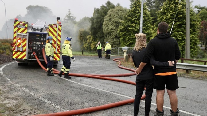 A couple watch on as fire fighters battle house blaze. Photo / George Heard
