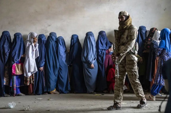A Taliban fighter stands guard as women wait to receive food rations distributed by a humanitarian aid group, in Kabul. Photo / AP