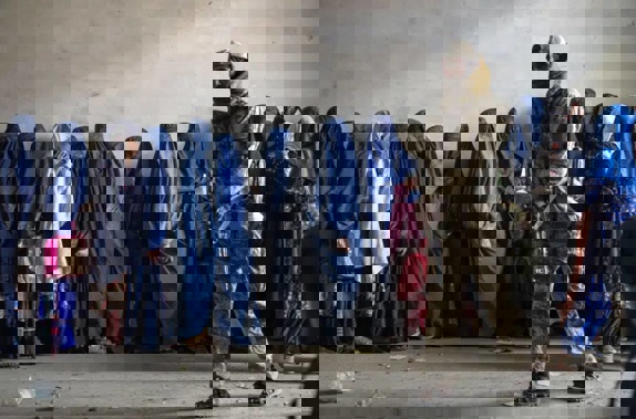 A Taliban fighter stands guard as women wait to receive food rations distributed by a humanitarian aid group, in Kabul. Photo / AP