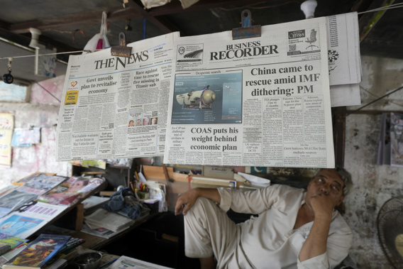 A vendor sits beside a copy of a morning newspaper which reports missing Titanic submersible and onboard five people, including Pakistani nationals Shahzada Dawood and his son Suleman, at a stall, in Karachi, Pakistan on June 21, 2023. Photo / AP
