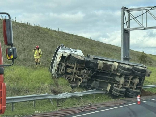 A truck carrying some 10 tonnes of dirt rolled over a barrier on the Southwestern Motorway. Photo / Anupinder Singh Sidhu