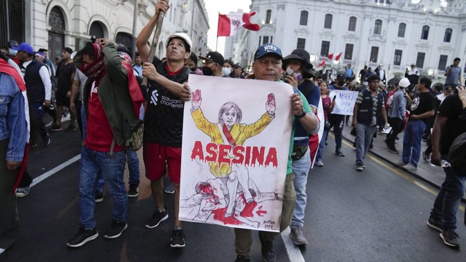 Supporters of ousted President Pedro Castillo hold a poster depicting Peru's new president along with sign "Killer" during a protest in Peru this week. Photo / AP