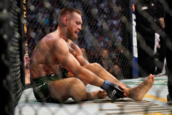 Conor McGregor holds his injured ankle after his defeat to Dustin Poirier at UFC 264. Photo / AP
