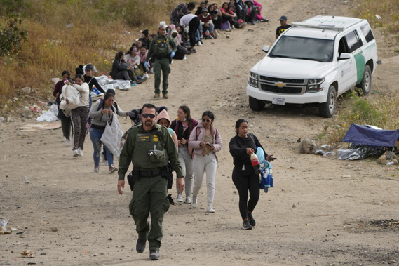 U.S. Border Patrol agent leads a line of women to a van as they wait to apply for asylum between two border walls in San Diego. Photo / AP