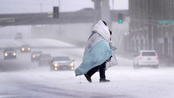 A person wrapped in a blanket crosses a snow-covered street in St Louis. Photo / AP