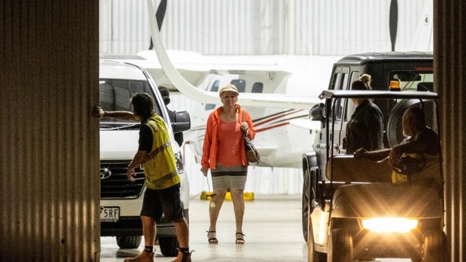 A woman believed to be Shane Warne's mother holds a white rose inside the hangar after his body returned to Australia. (Photo / News Corp Australia)
