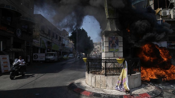Tyres burn during an Israeli military raid in the militant stronghold of Jenin refugee camp in the occupied West Bank. Photo / AP