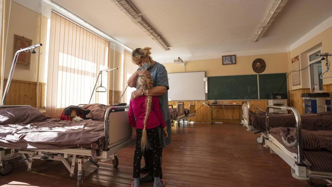 Nadia holds her 10-year-old granddaughter Zlata Moiseinko, suffering from a chronic heart condition, as she receives treatment at a schoolhouse that has been converted into a hospital. Photo / AP