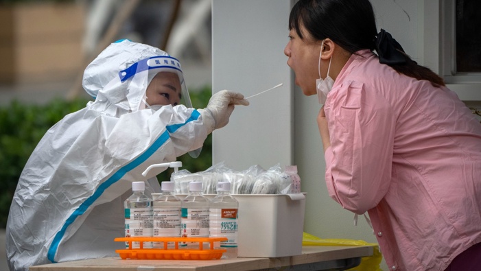 A worker wearing a protective suit swabs a woman's throat for a COVID-19 test at a coronavirus testing site in Beijing, Thursday, June 9, 2022. (Photo / AP)