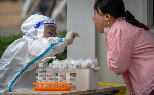 A worker wearing a protective suit swabs a woman's throat for a COVID-19 test at a coronavirus testing site in Beijing, Thursday, June 9, 2022. (Photo / AP)