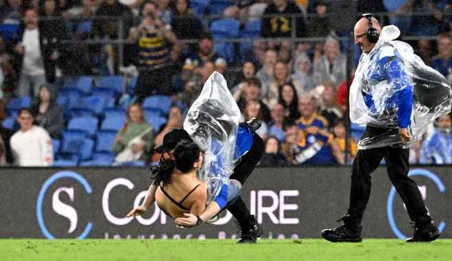 The pitch invader is tackled by a security guard. (Photo / Getty)