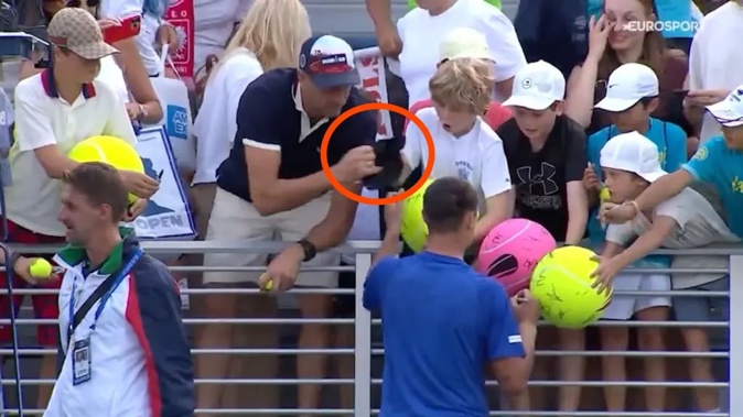 A man snatches a cap from a young fan at the US Open.