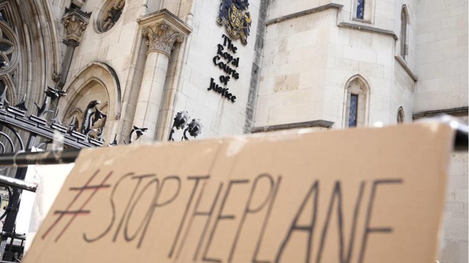 A placard left outside the High Court where the ruling on Rwanda deportation flights is taking place. Photo / AP