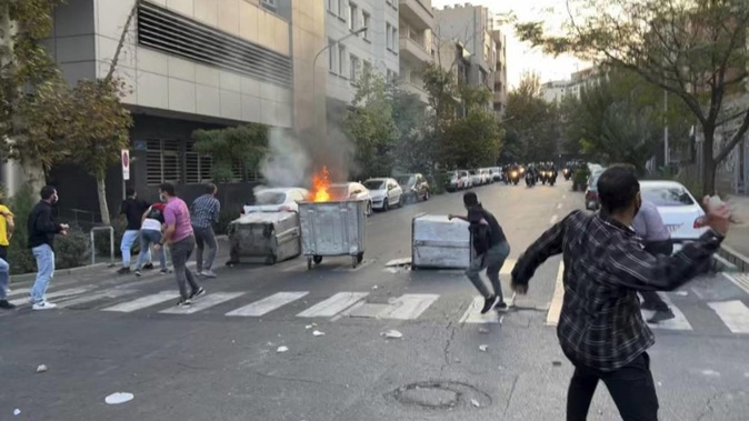 Protesters throw stones at anti-riot police during a protest over the death of a young woman who had been detained for violating the country's conservative dress code. Photo / AP