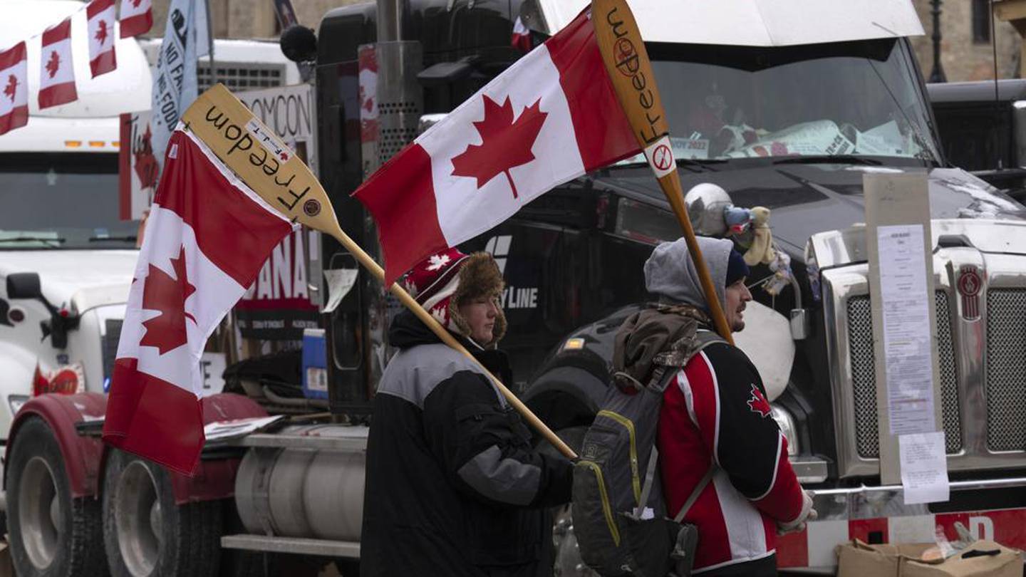 Surrounded by trucks, two protesters carry canoe paddles as flagpoles. Photo / AP