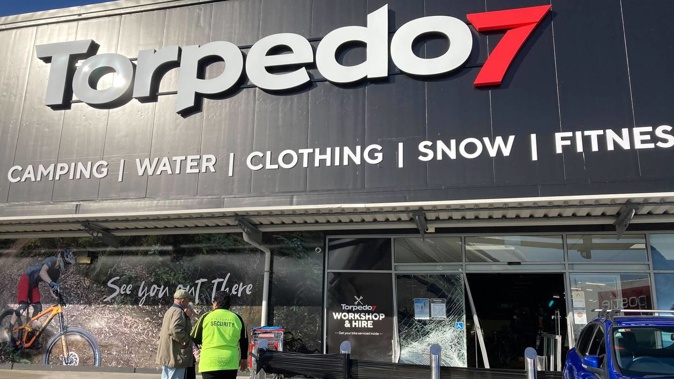 Bystanders and security stand outside the ram-raided store front of Torpedo7 Whangārei. Photo / Jaime Lyth