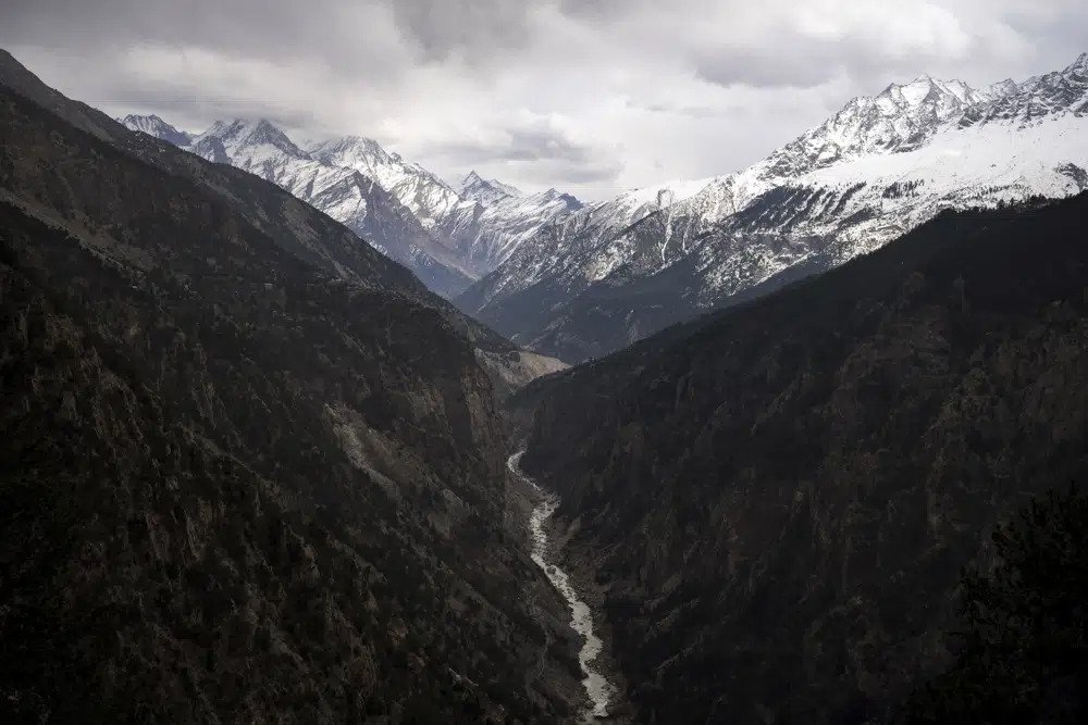 The Sutlej River flows in the valley below the tall snowy peaks in the Kinnaur district of the Himalayan state of Himachal Pradesh, India, March 13, 2023. A new report Tuesday, June 20, from a Nepal-based research organization finds that water security for nearly 2 billion people living downstream of rivers that originate in the Himalayan ranges will likely be threatened by the end of this century due to rapid glacier melt if global warming is not controlled. (AP Photo/Ashwini Bhatia, File)