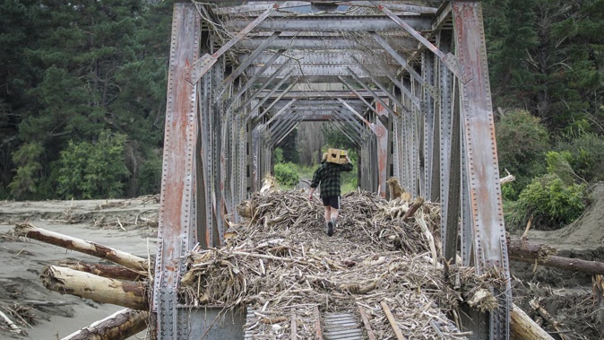 Sam Parsons delivering supplies to an isolated mate across the Esk River in Eskdale, using the only remaining passage across to the other end of Ellis Wallace Rd. Photo / Paul Taylor