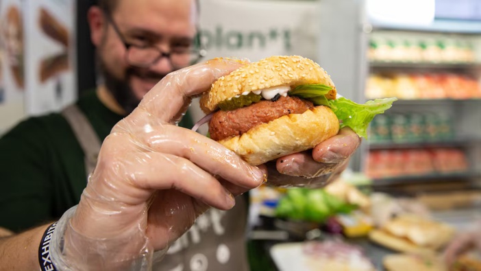 Kyran Rei, co-founder of Sustainable Foods, holds a vegan burger at the plan*t stall during a food show at the Auckland Showgrounds.