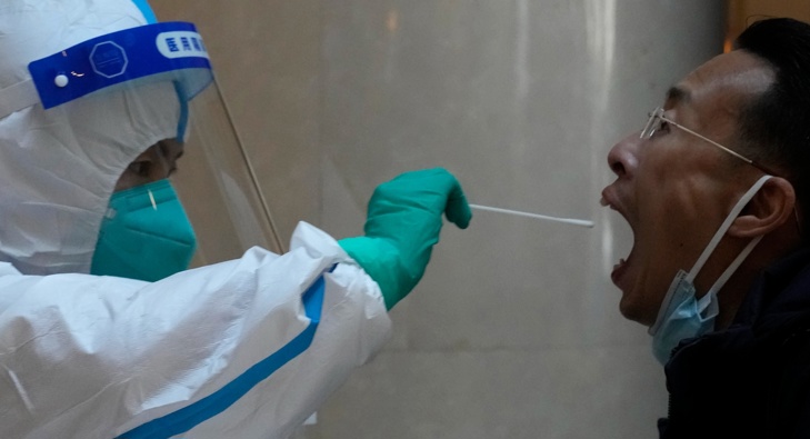 A worker prepares to take swab sample from a man before quarantine for a government event at a hotel on Thursday, April 7, 2022, in Beijing. (Photo / AP)