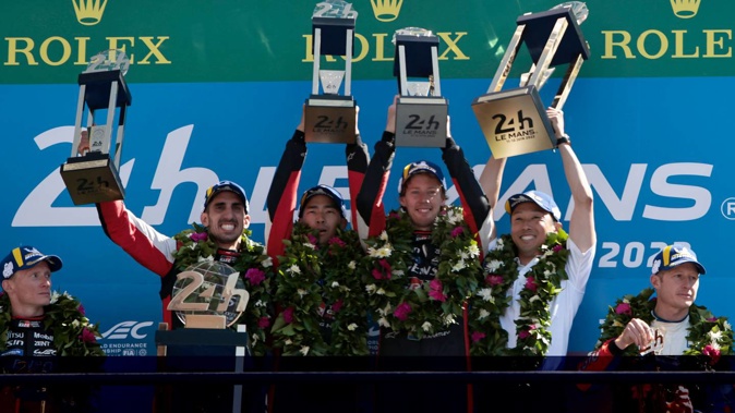 Sebastien Buemi of Switzerland, left, Brendon Hartley, center right, and Ryo Hirakawa of Japan, center left, hold their trophies after winning the 24-Hour Le Mans endurance race. Photo / AP