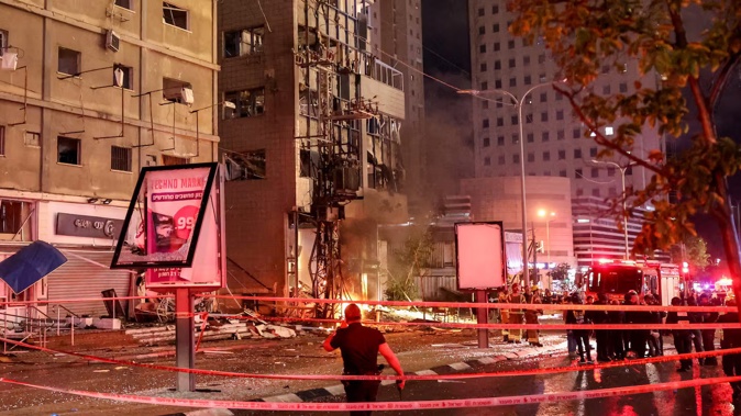 Israeli security services stand in front of a heavily damaged building at the site of a rocket attack from southern Lebanon in Ramat Gan. Photo / AFP