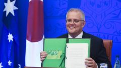 Australian Prime Minister Scott Morrison holds up a signed document during a virtual treaty signing summit with Japanese Prime Minister Fumio Kishida, at Parliament House, in Canberra. (Photo / AP)