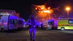 A Russian Rosguardia (National Guard) servicemen secures an area as a massive blaze seen over the Crocus City Hall. Photo / AP