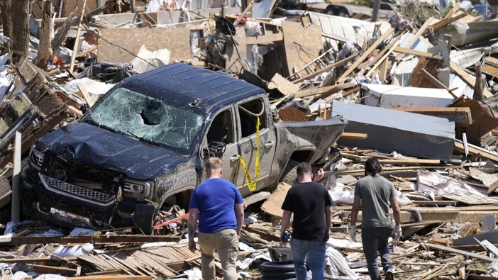 Local residents walk among the debris from tornado damaged homes, Wednesday, May 22, 2024, in Greenfield, Iowa. (AP Photo/Charlie Neibergall)