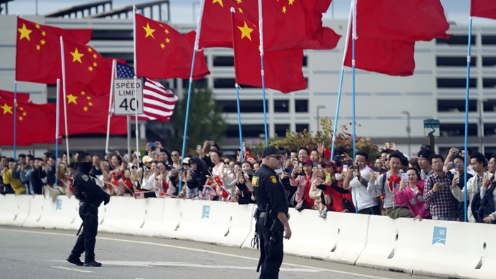 With American and Chinese flags flying, people watch as the motorcade carrying President Joe Biden drives past Tuesday, Nov. 14, 2023, in San Francisco. Photo / AP