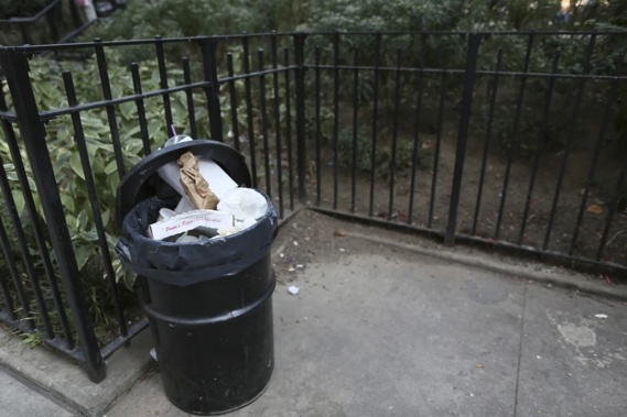 In this Thursday, Sept. 17, 2015, photo, an open and overflowing garbage container is seen next to a park in the Chinatown neighborhood of New York. As of Friday, March 1, 2024, all 200,000 businesses in the Big Apple are required to put out their bags of trash in garbage bins, as communities across the county and world have long done. (AP Photo/Mary Altaffer, File)