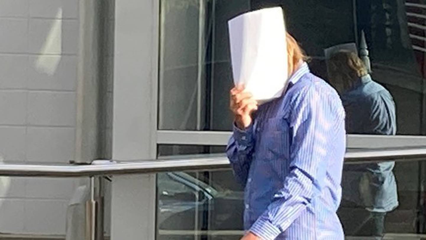 Ian Engelbrecht hides his face when leaving the Nelson District Court after he was sentenced for performing an indecent act. (Photo / Tracy Neal)
