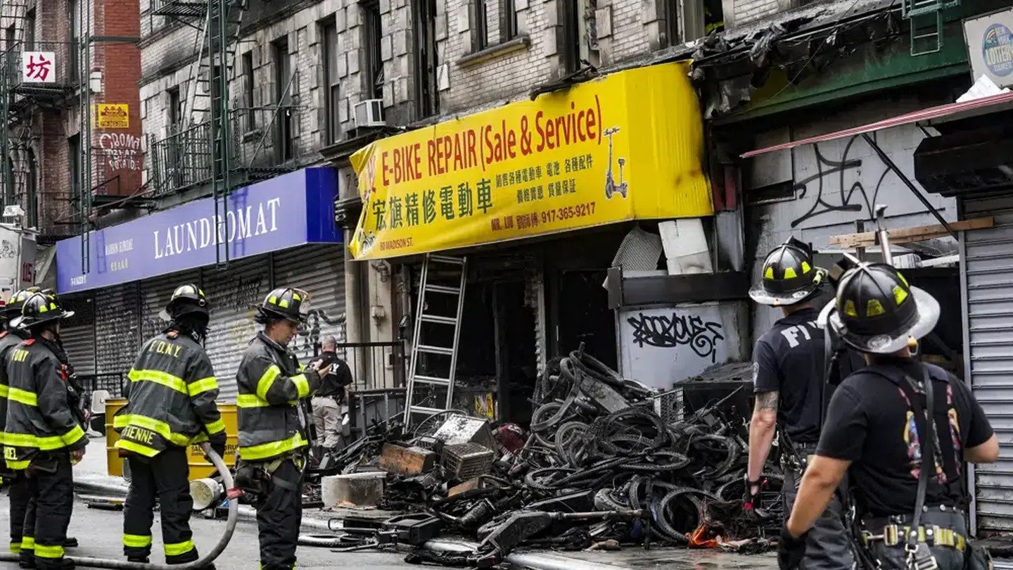 Firefighters and investigators go through the aftermath of a fire which authorities say started at an e-bike shop and spread to upper-floor apartments. Photo / AP