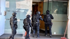Squads of police officers with rifles and tactical gear went into the Goodview Apartment Hotel after a gun sighting. Photo / RNZ / Marika Khabazi