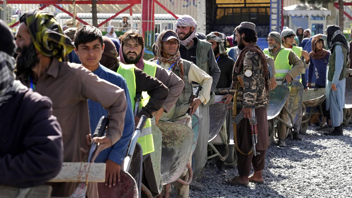 A Taliban fighter stands guard as people wait to receive food rations in Kabul where authorities have reinstated lashings as punishment for theft. Photo / AP