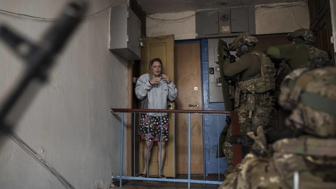 A woman looks as Security Service of Ukraine (SBU) servicemen enter a building during an operation to arrest suspected Russian collaborators in Kharkiv, Ukraine, Thursday, April 14, 2022. (Photo / AP)