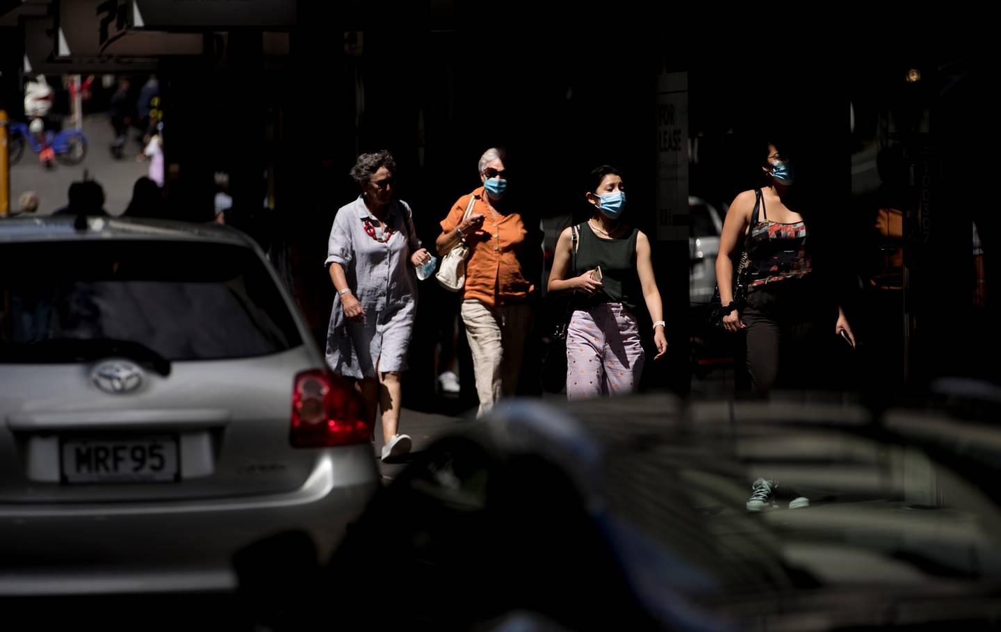 People out and about in Auckland's CBD wear face masks, but 1218 people in the region are isolating at home. (Photo / Dean Purcell)